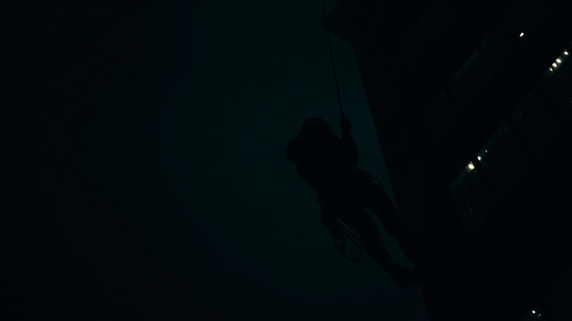 Certified rope access technician performing high rise building maintenance at night on an Ontario commercial property